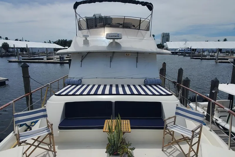 Slide: The Image of 1981 Hatteras 56 Motor Yacht with striped seating, docked at a marina. - 2