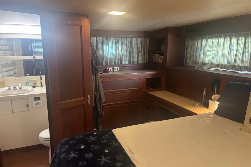 Slide: The Image of 1981 Hatteras 56 Motor Yacht interior with wood paneling, bed, and bathroom. - 25