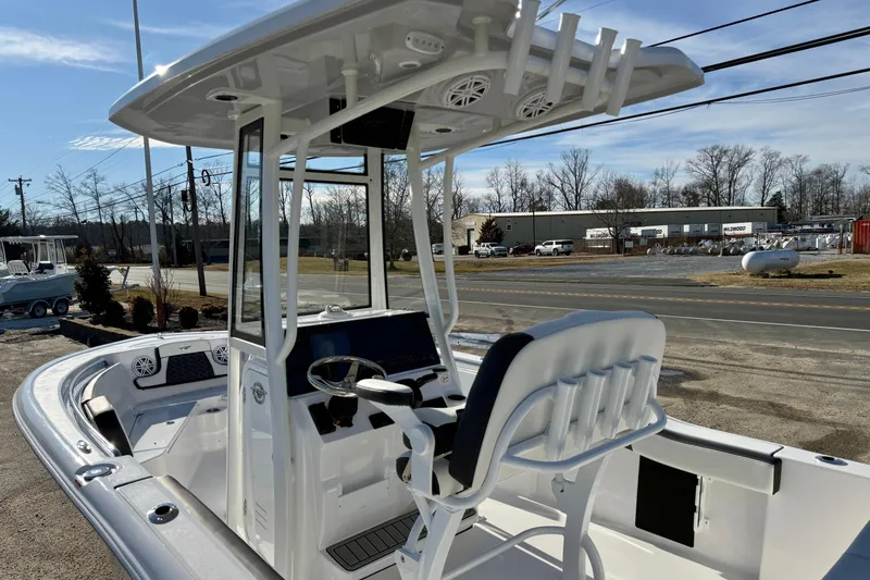 Slide: The Image of 2026 Tidewater 210 CC Adventure boat with modern console and seating, parked outdoors. - 11
