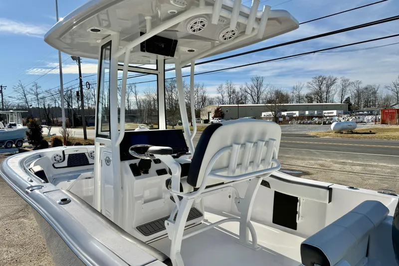 Slide: The Image of 2026 Tidewater 210 CC Adventure boat with T-top and seating, parked outdoors. - 9