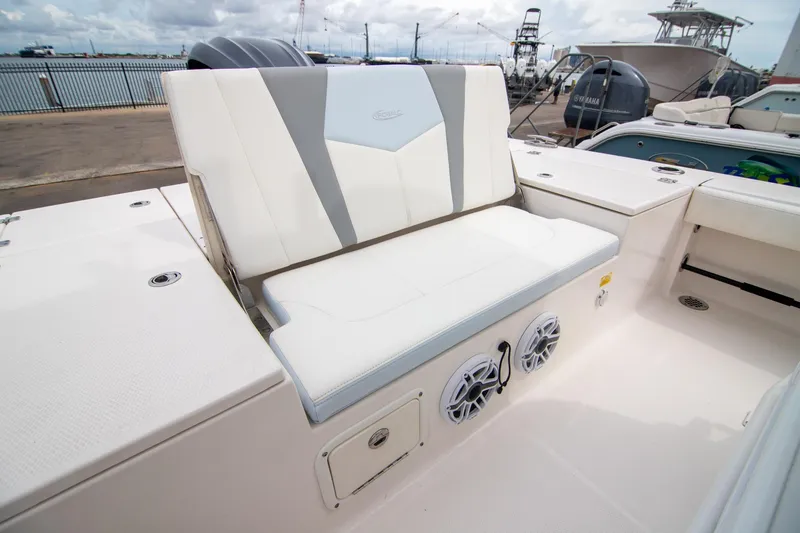 Slide: The Image of 2023 Robalo 246 Cayman boat seating area with speakers, docked at marina. - 14