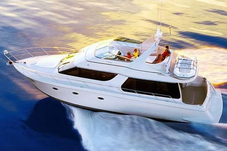 Slide: The Image of 1998 Carver 530 Voyager Pilothouse yacht cruising on open water at sunset. - 2