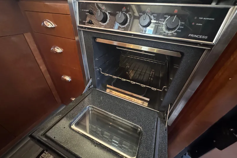 Slide: The Image of 1998 Carver 530 Voyager Pilothouse kitchen with open oven and control knobs. - 64