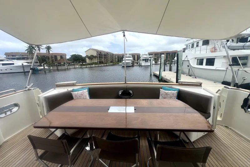 Slide: The Image of Outdoor dining area on 2009 Nordhavn N78 yacht, featuring a wooden table and marina view. - 13