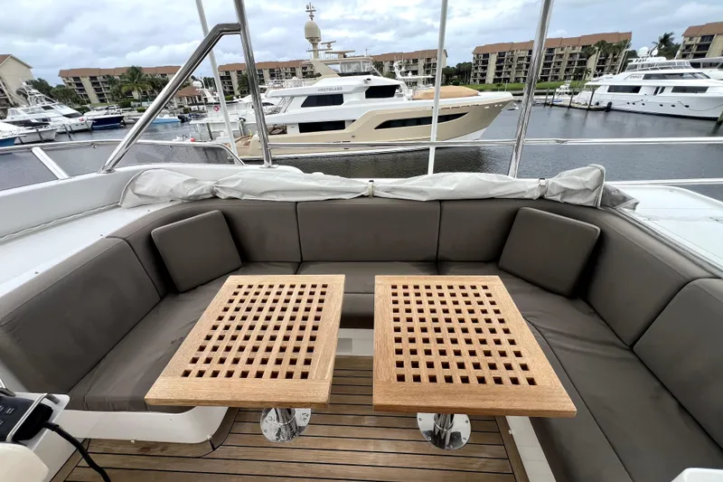 Slide: The Image of Luxurious 2009 Nordhavn N78 yacht deck with cushioned seating and wooden tables, docked at marina. - 28