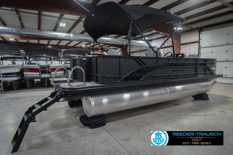 Slide: The Image of 2026 Bennington 21 SF pontoon boat in showroom with black canopy and ladder. - 8
