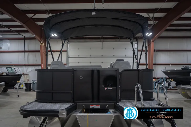 Slide: The Image of 2026 Bennington 21 SF pontoon boat in showroom, rear view with canopy and ladder. - 9