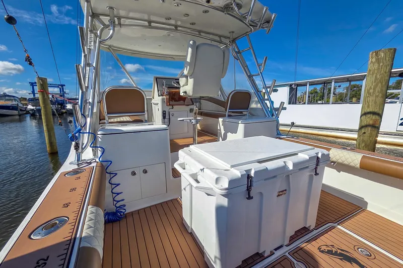 Slide: The Image of 2005 Egg Harbor 35' Express boat interior with seating and storage, docked under clear blue sky. - 30