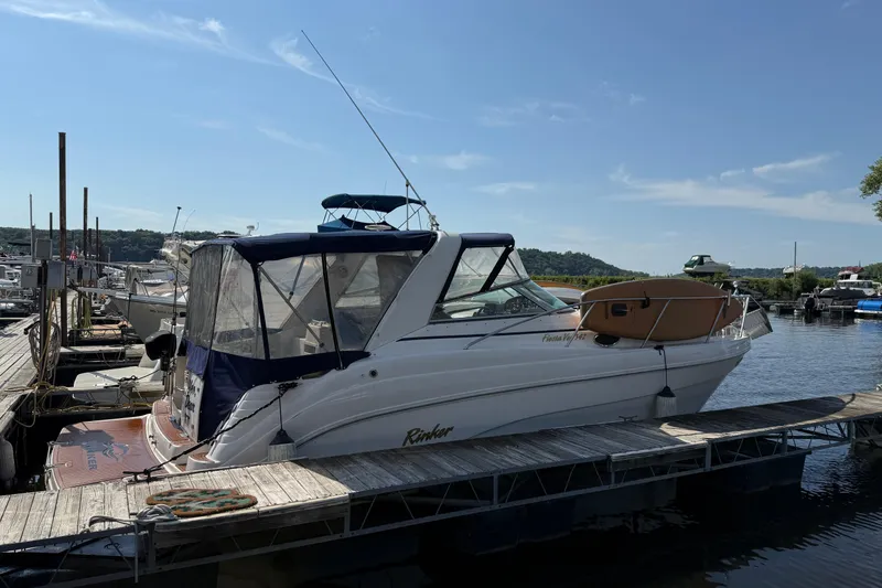 The Image of 2002 Rinker 342 Fiesta Vee boat docked at a marina under a clear blue sky. - 0
