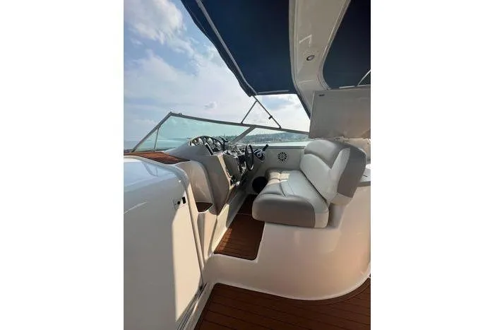 Slide: The Image of 2002 Rinker 342 Fiesta Vee boat interior with seating and steering, under blue canopy. - 13