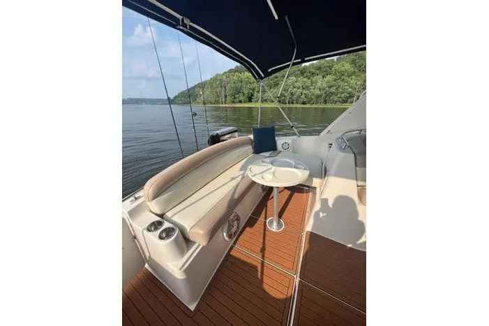 Slide: The Image of 2002 Rinker 342 Fiesta Vee boat interior with seating and table on a calm lake. - 15