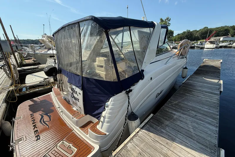 Slide: The Image of 2002 Rinker 342 Fiesta Vee docked at marina, featuring covered cockpit and wooden deck. - 2