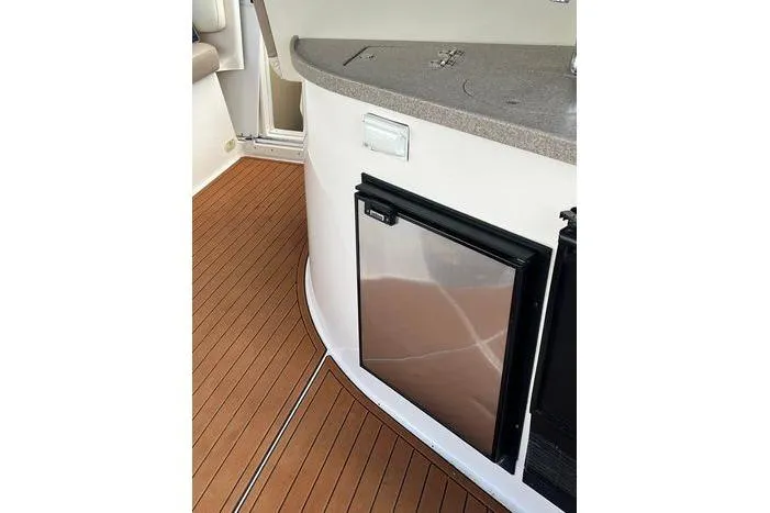 Slide: The Image of 2002 Rinker 342 Fiesta Vee boat interior with compact fridge and wooden flooring. - 5