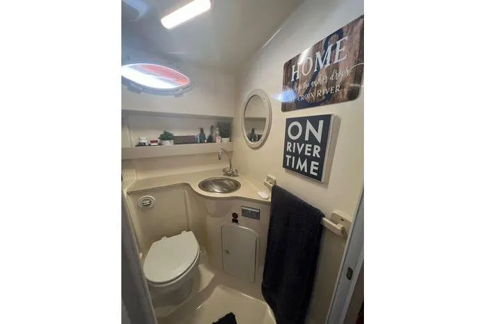 Slide: The Image of 2002 Rinker 342 Fiesta Vee bathroom with sink, toilet, and decorative signs. - 6