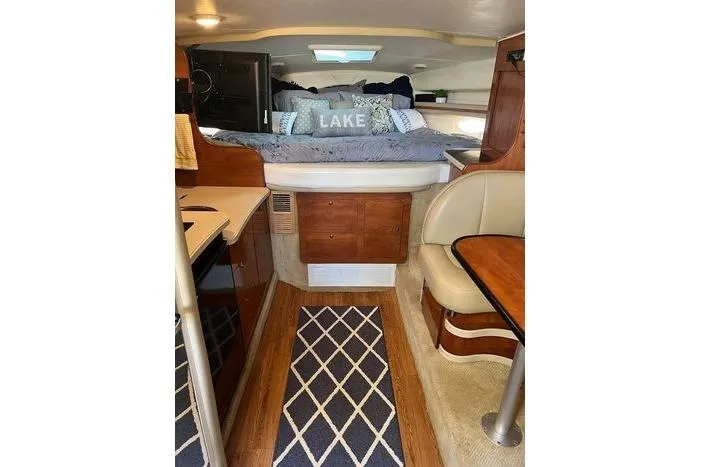 Slide: The Image of 2002 Rinker 342 Fiesta Vee cabin interior with cozy bed and dining area. - 8