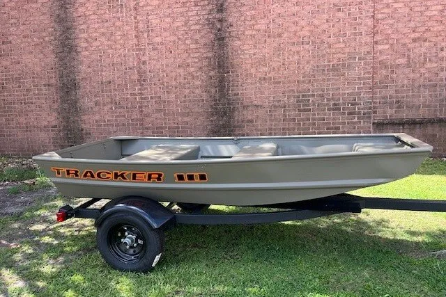 The Image of 2026 Tracker Grizzly 10 Jon boat on trailer, parked on grass by brick wall. - 0