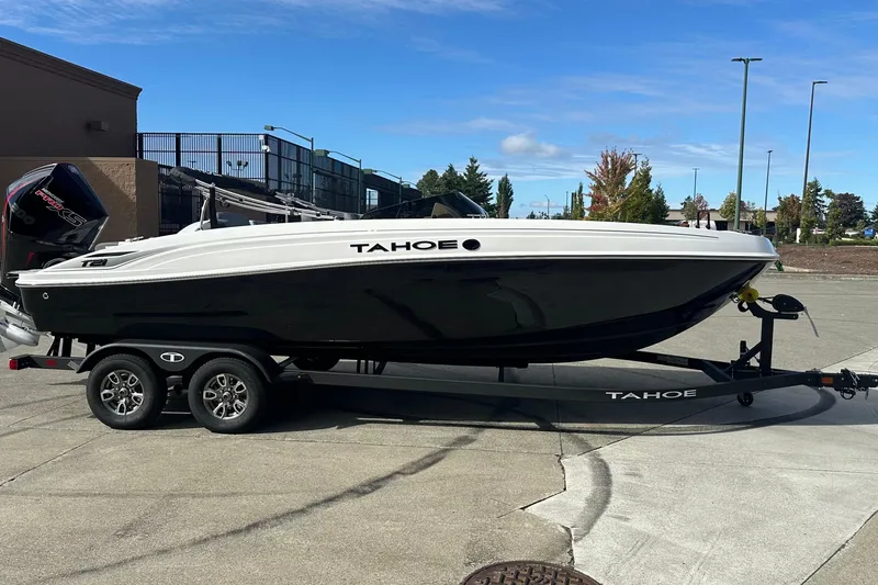 The Image of 2026 Tahoe T21 boat on trailer, black and white design, parked outdoors. - 0