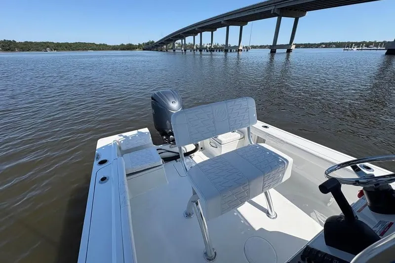 Slide: The Image of 2026 Parker 180 Coastal boat on calm water near a bridge, featuring sleek seating and controls. - 14