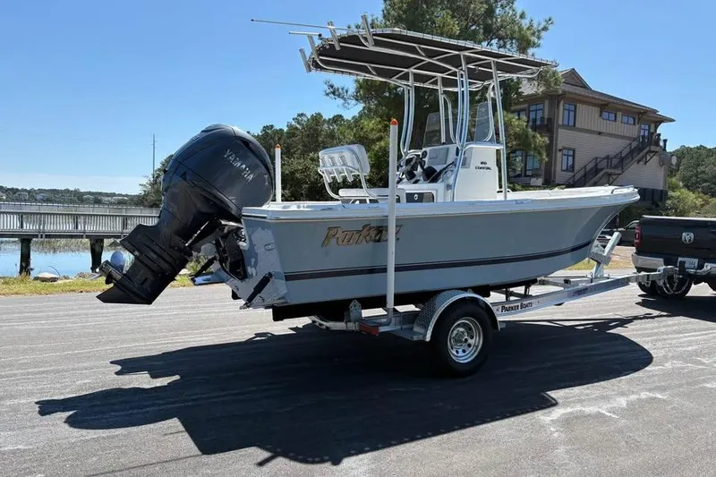 Slide: The Image of 2026 Parker 180 Coastal boat on trailer, parked near waterfront, with Yamaha outboard motor. - 2
