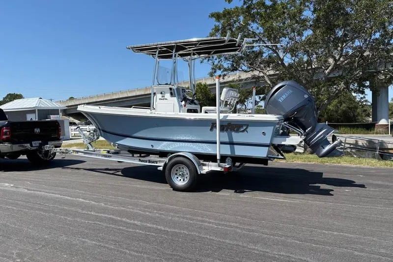 Slide: The Image of 2026 Parker 180 Coastal boat on trailer, parked outdoors near trees and a bridge. - 5