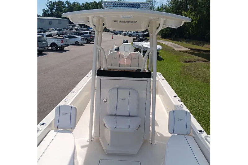 Slide: The Image of 2026 Ranger 2360 Bay boat interior with seating and console, parked outdoors. - 24