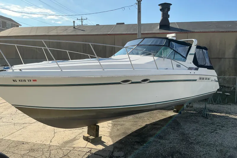 Slide: The Image of 1992 Wellcraft 3400 Gran Sport boat on dry dock, white hull, blue canopy, sunny day. - 5