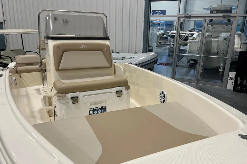 Slide: The Image of 2025 Scout 175 Sportfish boat interior with beige seating and console in showroom. - 10