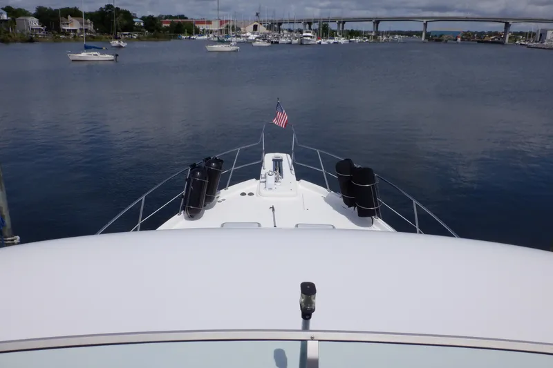 Slide: The Image of 1998 Bayliner 4788 Pilot House Motoryacht on calm water with bridge and marina view. - 17