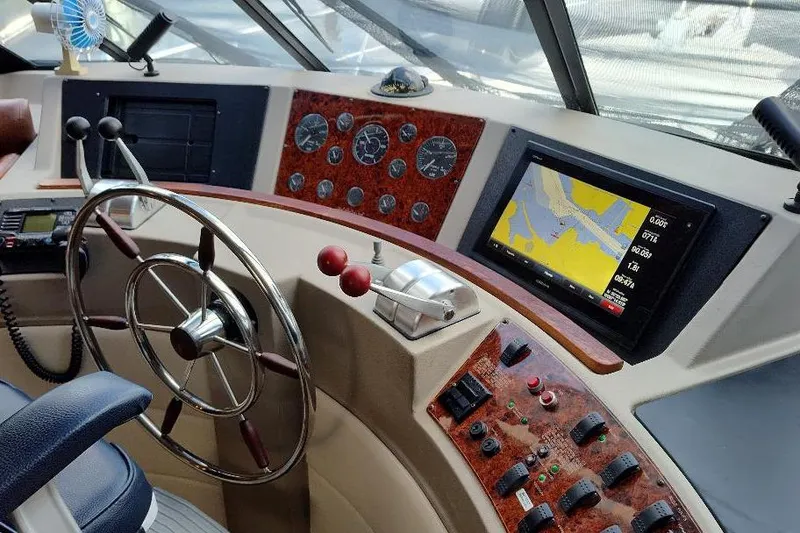 Slide: The Image of 1998 Bayliner 4788 Pilot House Motoryacht helm with navigation controls and steering wheel. - 48