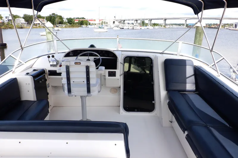 Slide: The Image of 1998 Bayliner 4788 Pilot House Motoryacht interior with helm, seating, and waterfront view. - 6