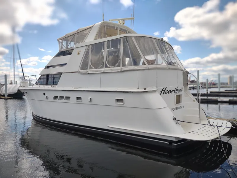 Slide: The Image of 1996 Hatteras 50' Sport Deck yacht docked in a marina under a partly cloudy sky. - 2