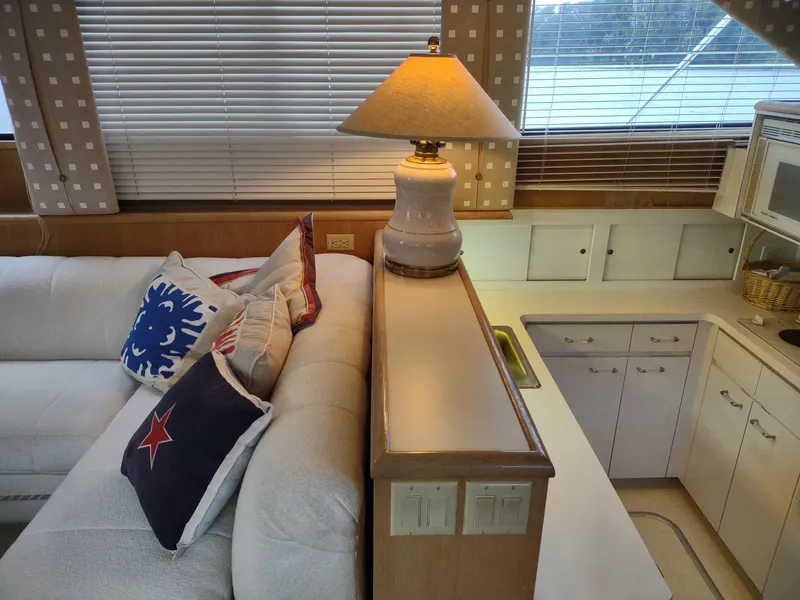 Slide: The Image of Interior of 1996 Hatteras 50' Sport Deck with cozy seating, decorative pillows, and a lamp. - 25
