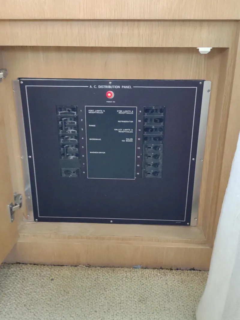 Slide: The Image of 1996 Hatteras 50' Sport Deck AC distribution panel in wooden cabinet. - 28