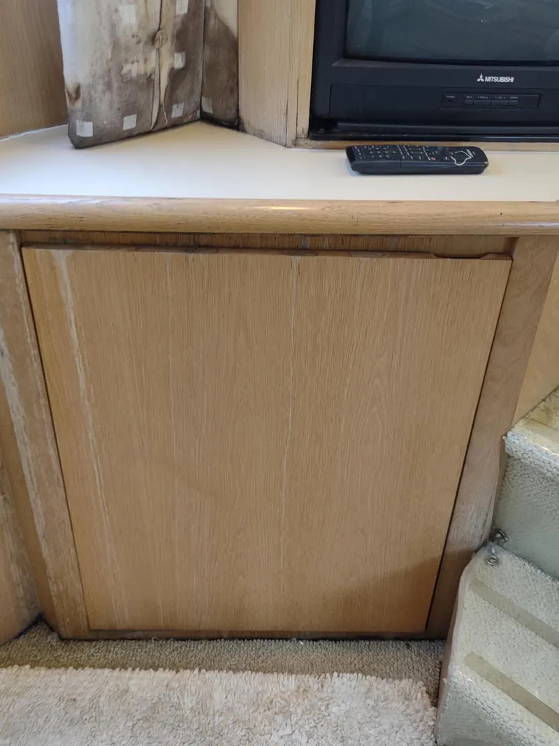 Slide: The Image of 1996 Hatteras 50' Sport Deck interior with TV, remote, and wooden cabinet. - 35