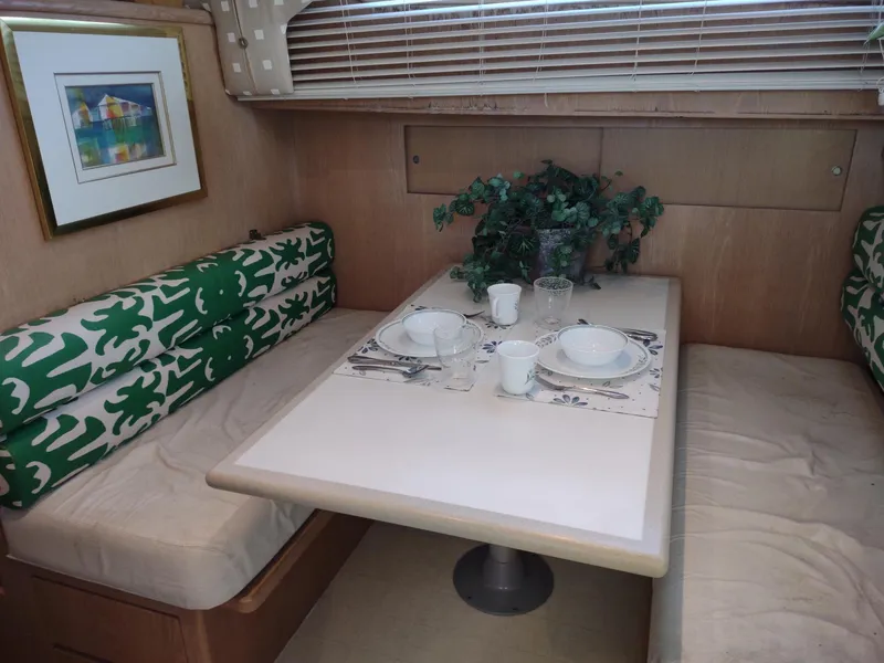 Slide: The Image of 1996 Hatteras 50' Sport Deck interior dining area with green patterned cushions and table setting. - 39