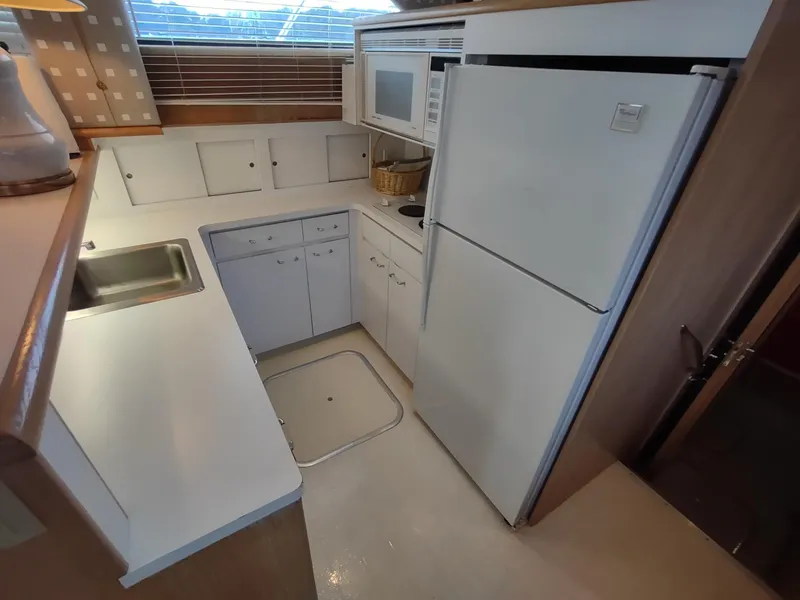 Slide: The Image of 1996 Hatteras 50' Sport Deck kitchen with white cabinetry, fridge, and microwave. - 42