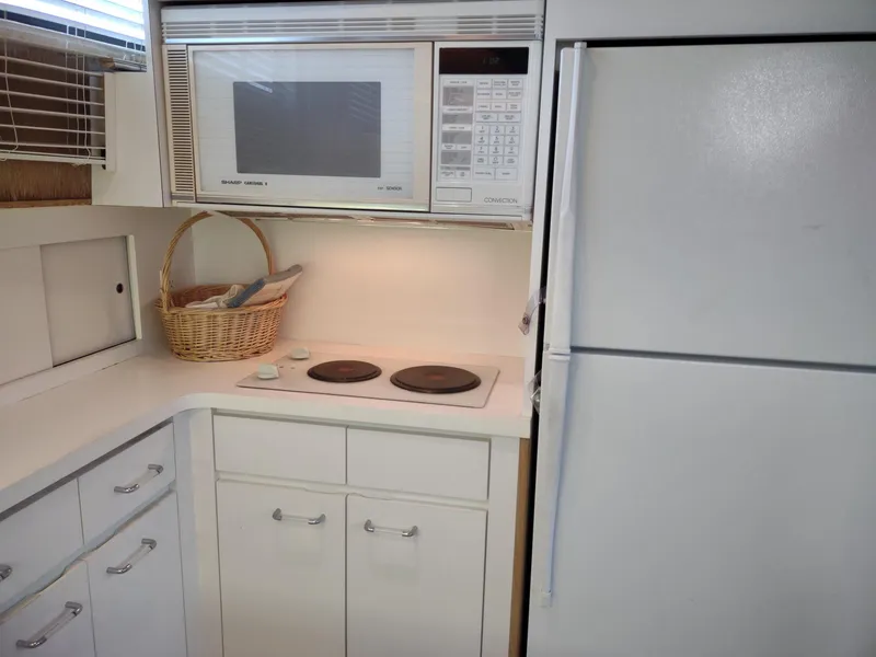 Slide: The Image of Kitchen area of 1996 Hatteras 50' Sport Deck with microwave, stove, and refrigerator. - 43