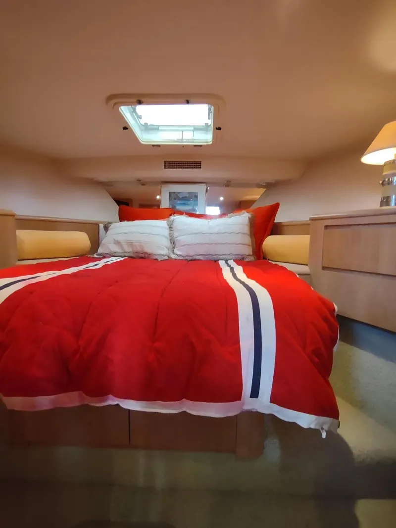 Slide: The Image of Cozy bedroom in 1996 Hatteras 50' Sport Deck yacht with red bedding and natural light. - 48