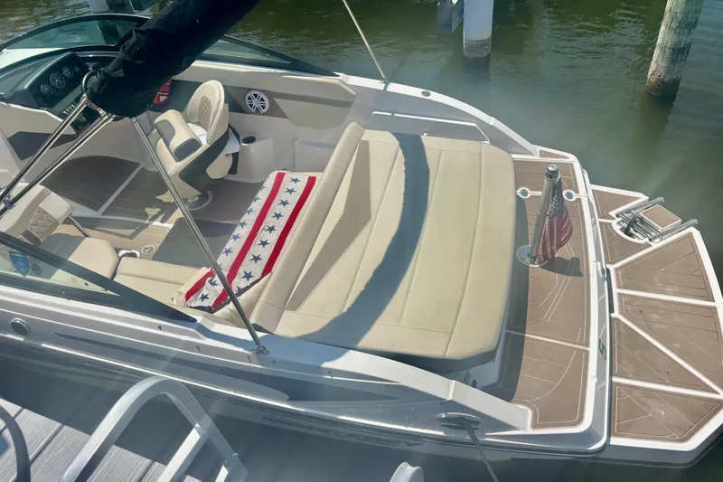 Slide: The Image of 2024 Monterey M-20 boat interior with seating, American flag, and dashboard, docked on water. - 9