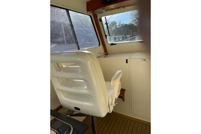 Slide: The Image of Interior of 2009 Eastern 248 Explorer boat with white captain's chair and window view. - 16