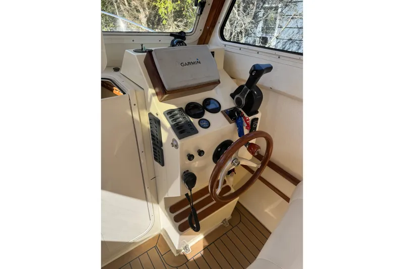 Slide: The Image of 2009 Eastern 24 boat helm with Garmin navigation, wooden steering wheel, and control panel. - 8