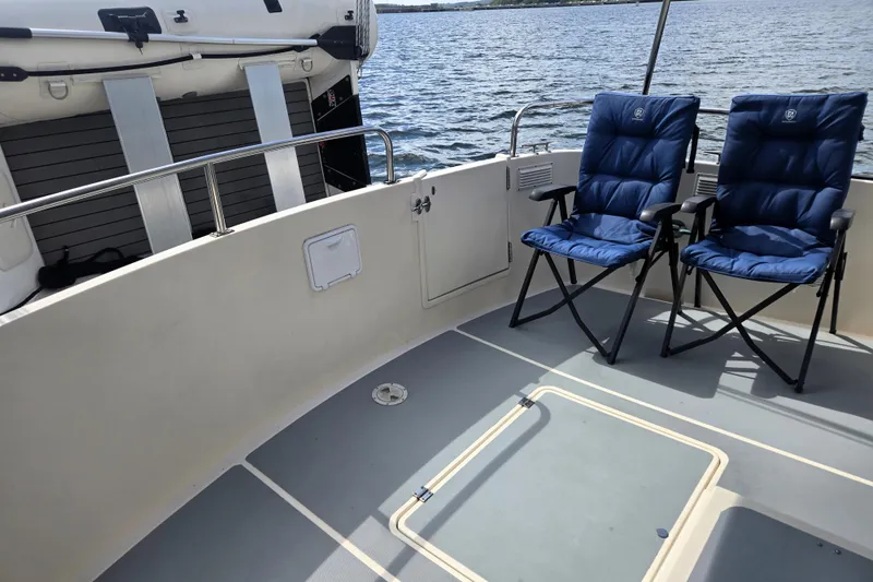 Slide: The Image of Nordic Tug 42 Flybridge 2000 with blue chairs on deck, overlooking water. - 12