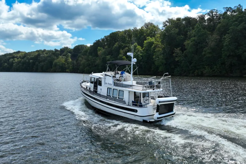 Slide: The Image of Nordic Tug 42 Flybridge 2000 cruising on a scenic lake under a blue sky. - 4