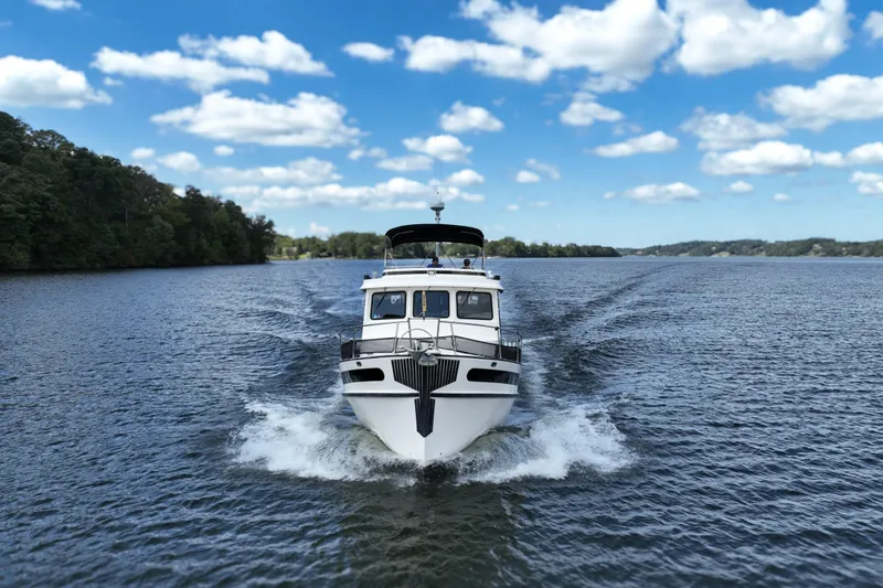 Slide: The Image of Nordic Tug 42 Flybridge 2000 cruising on a scenic lake under a blue sky. - 6