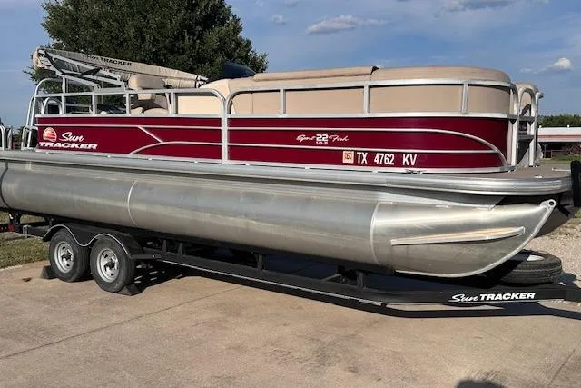 The Image of 2018 Sun Tracker SportFish 22 DLX pontoon boat on trailer, parked outdoors. - 1