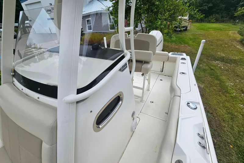 Slide: The Image of 2019 Boston Whaler 230 Outrage boat interior with seating and console, parked on grass. - 10