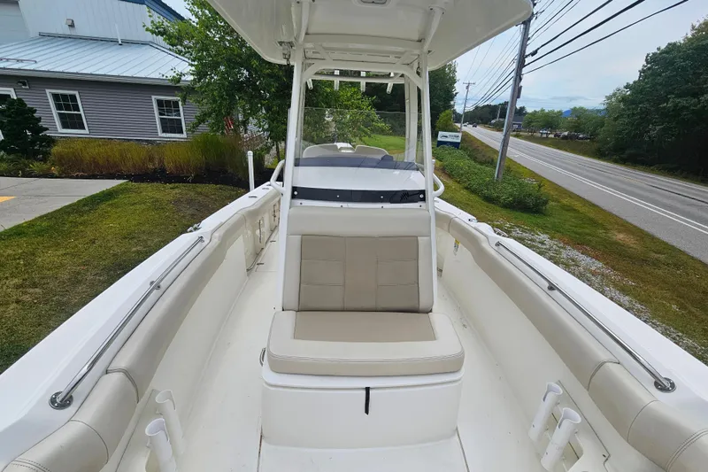 Slide: The Image of 2019 Boston Whaler 230 Outrage boat interior with seating and console, parked near a road. - 13