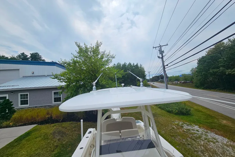 Slide: The Image of 2019 Boston Whaler 230 Outrage boat with T-top, parked near a road and greenery. - 14