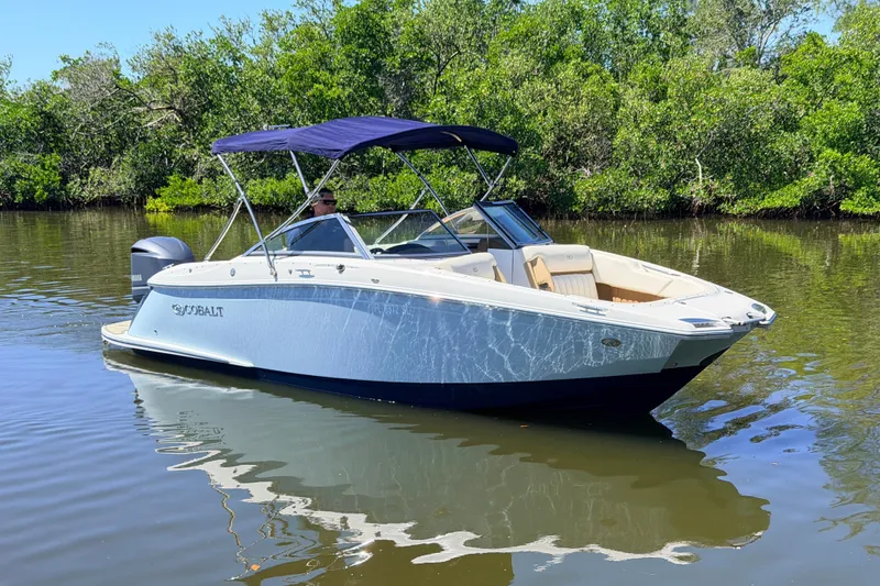The Image of 2018 Cobalt 23SC boat on calm water, surrounded by lush greenery. - 0