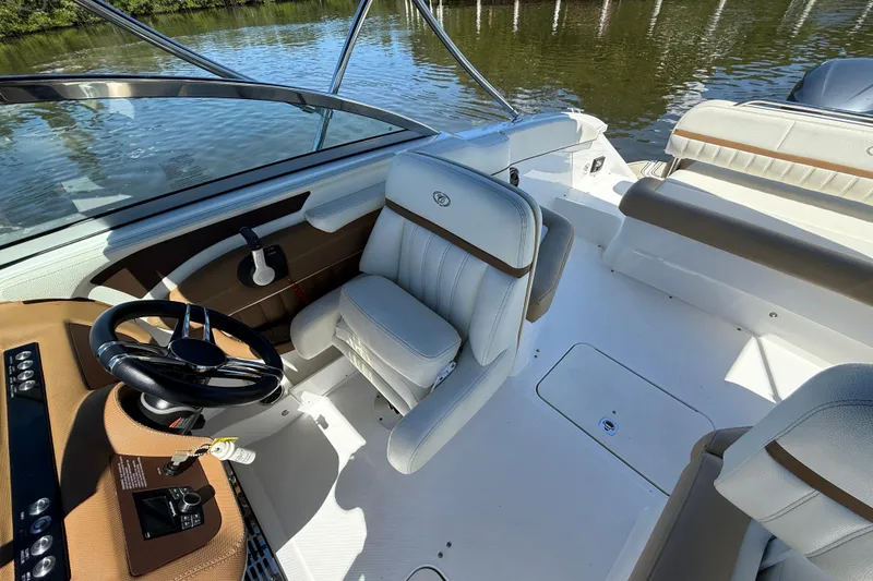 Slide: The Image of 2018 Cobalt 23SC boat interior with steering wheel and seating, on calm water. - 13